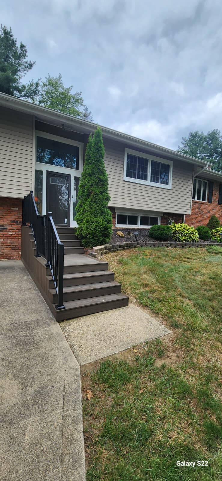 Finished front entry steps with black railings and landscaped yard